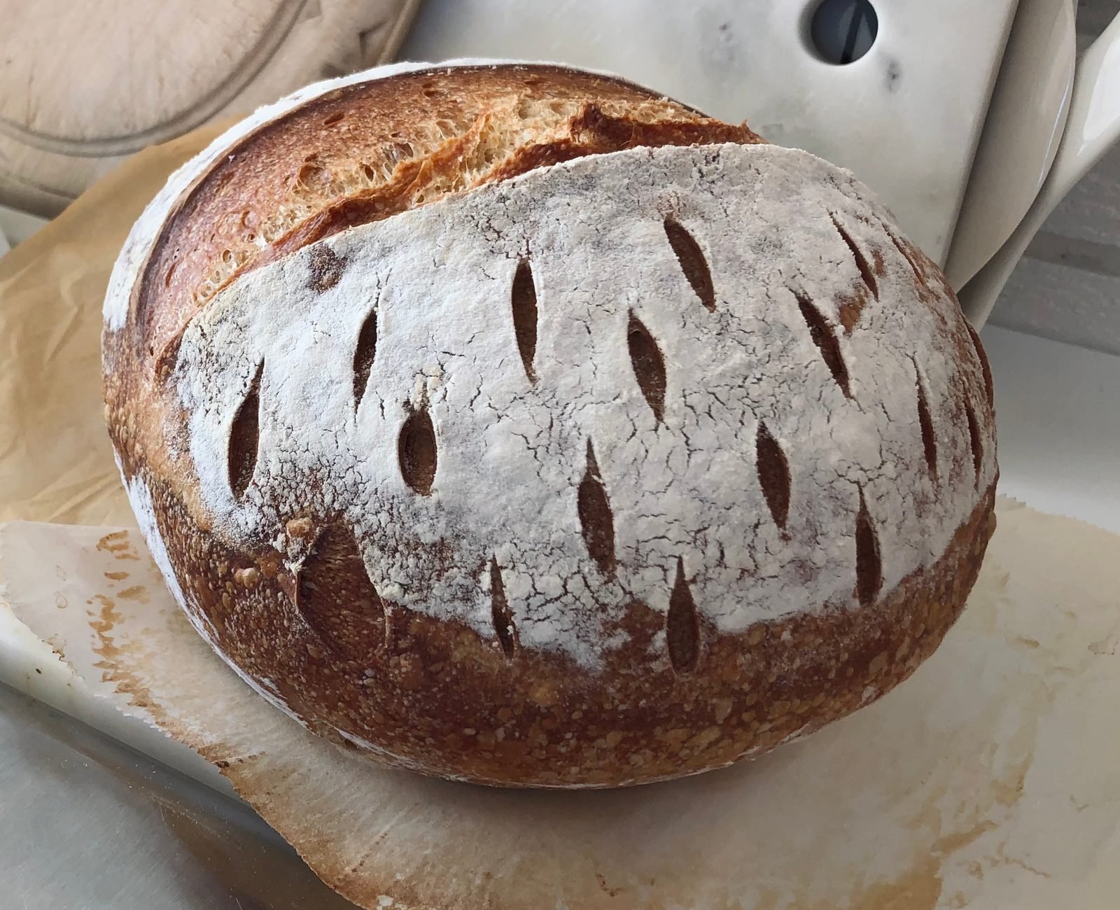 A round sourdough loaf, dusted with flour and scored in rows