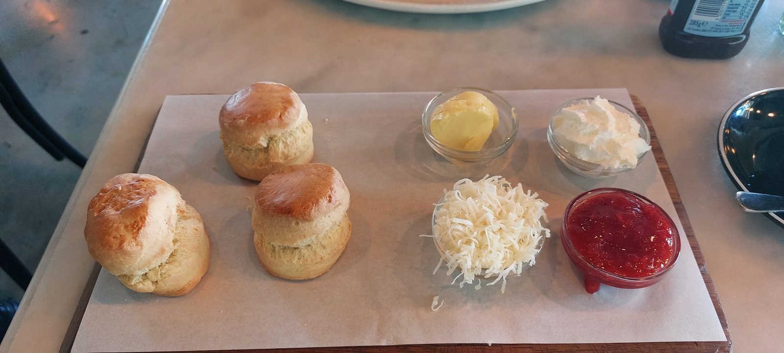 Scones on a tray, with butter and jam beside them