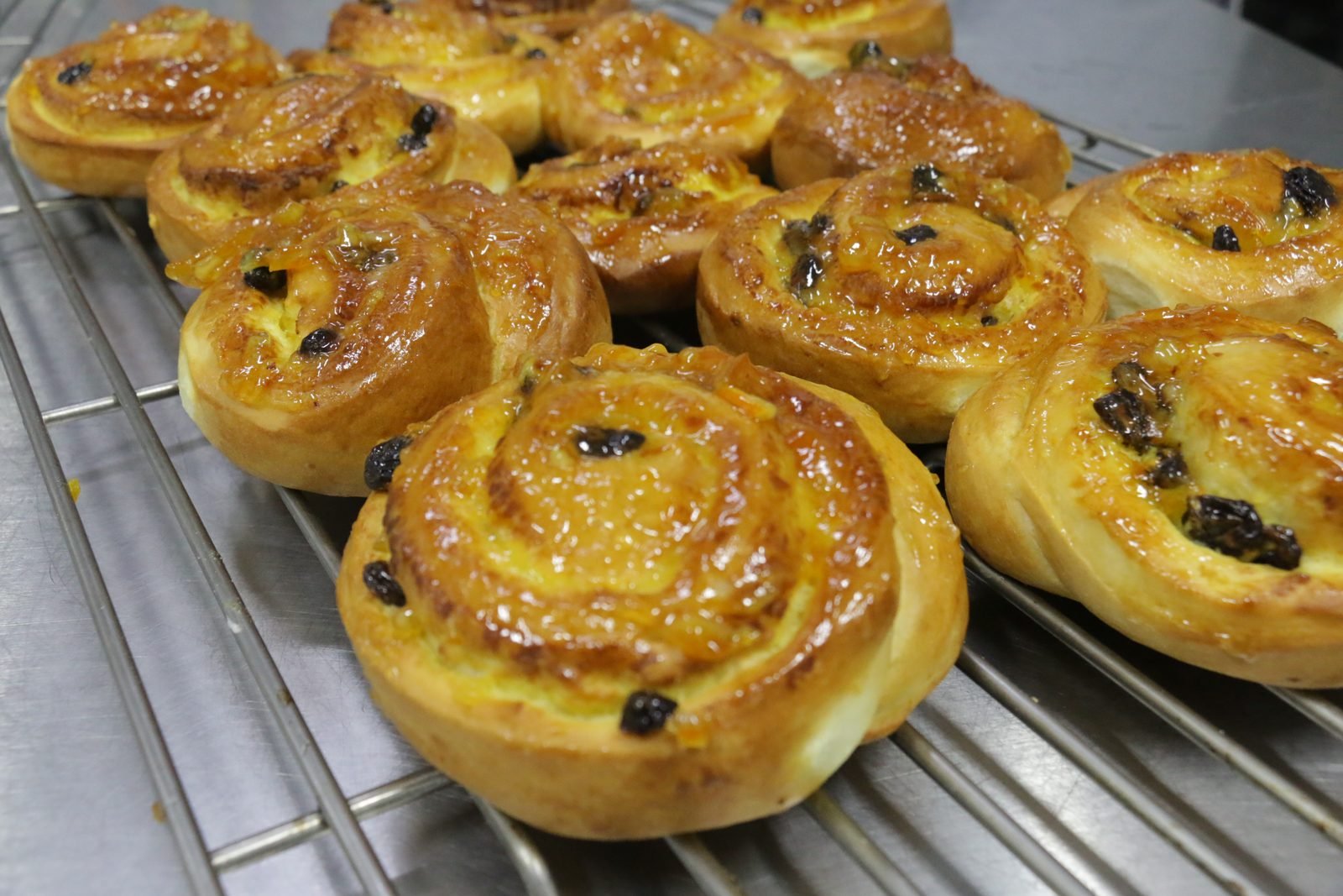 Glazed cinnamon buns with raisins on a rack