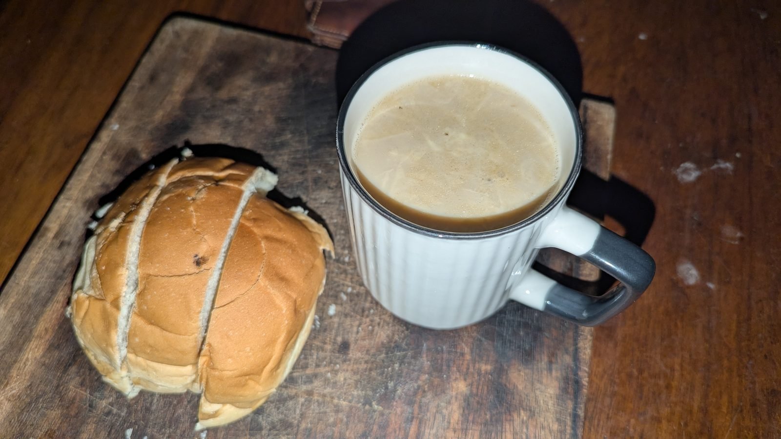 Buttered bread on a wooden board beside a cup of milk
