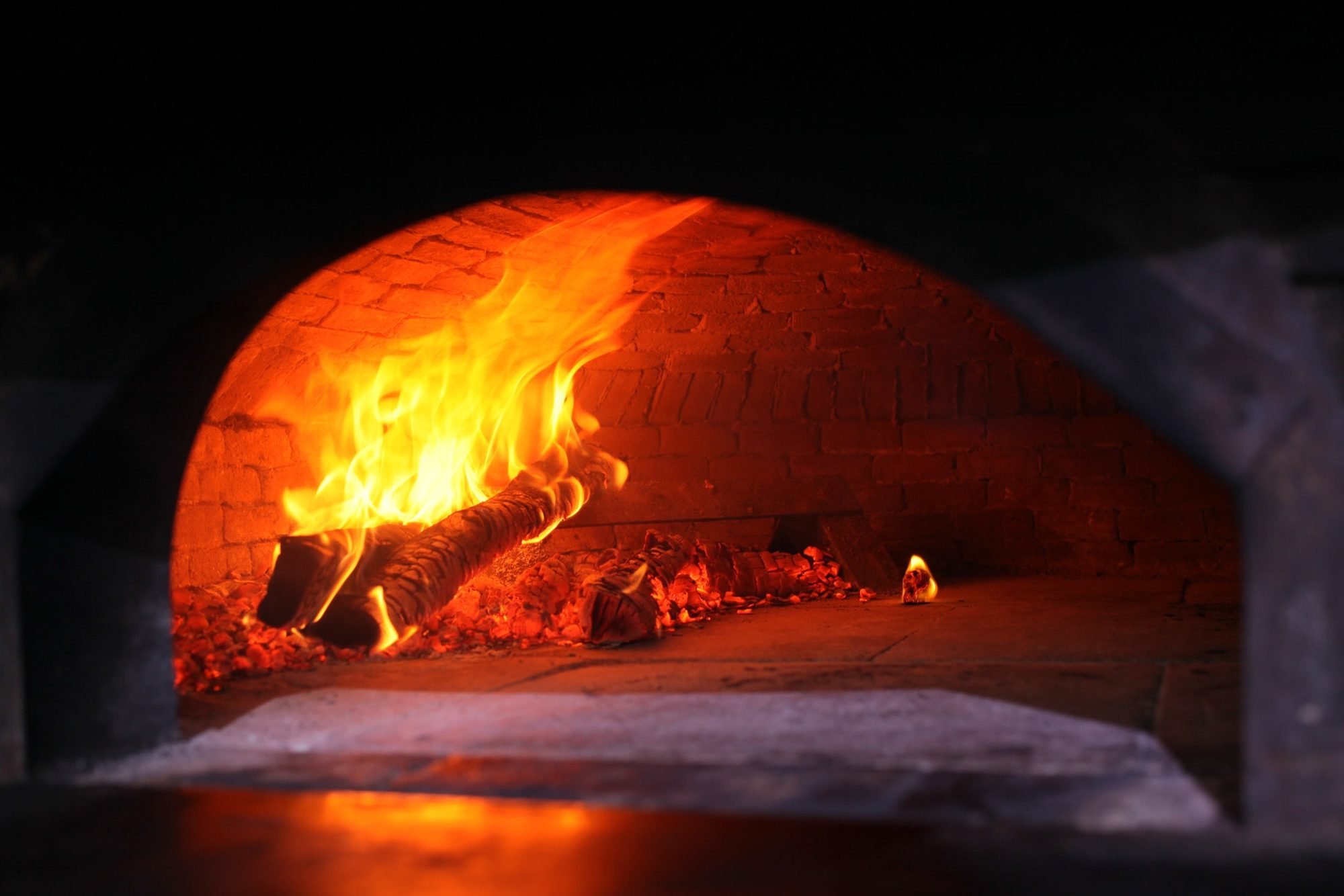 A wood fire burning inside a brick oven